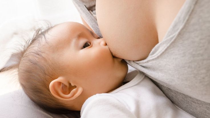 a close up of a baby being kissed by its mother's breastfeeding