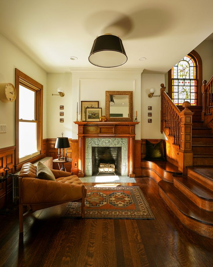 a living room filled with furniture and a fire place next to a stair case in front of a window