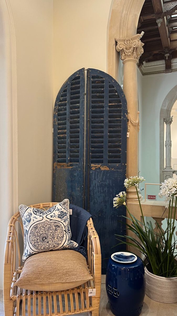 a room with a chair, mirror and potted plant on the floor in front of an arched doorway