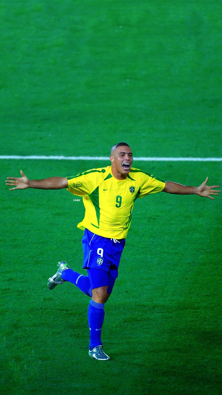 a soccer player in the air with his arms wide open as he prepares to kick the ball