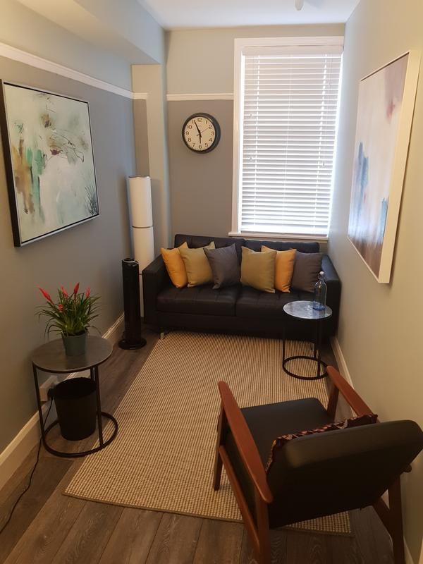 a living room filled with furniture and a clock mounted to the side of the wall