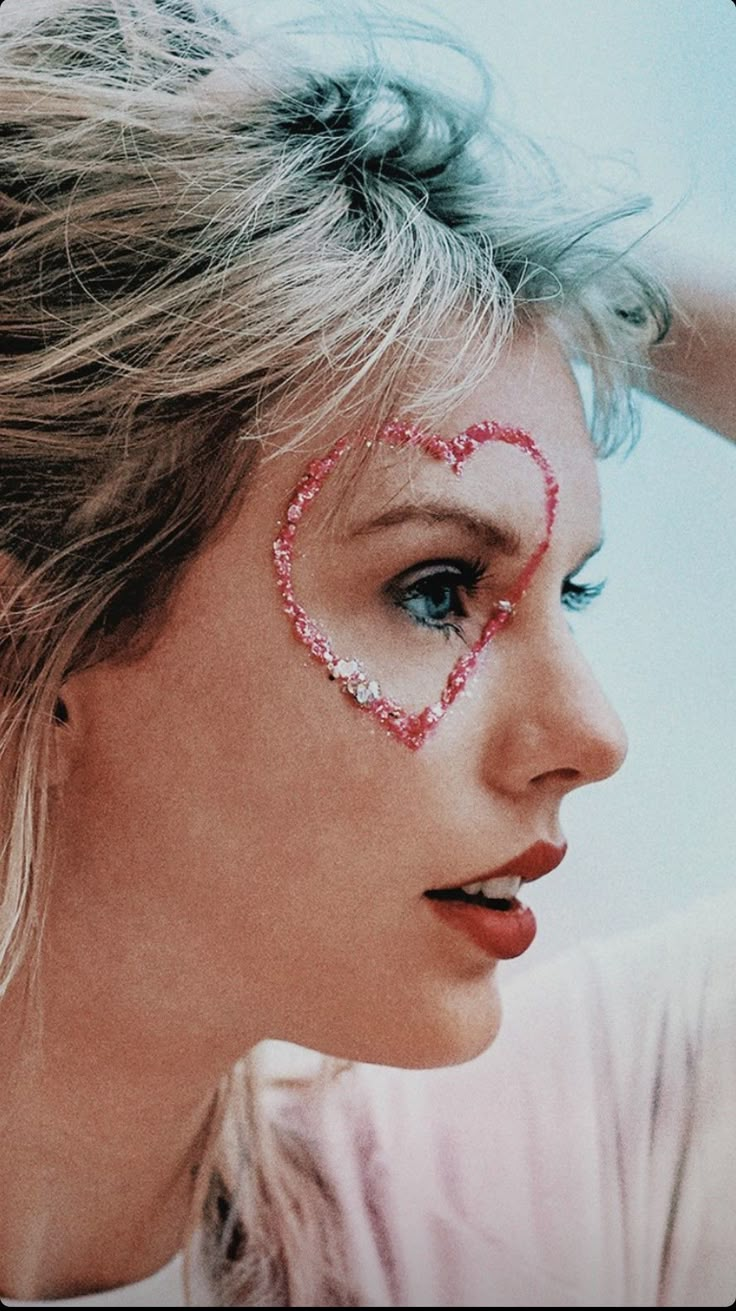 a woman with a heart painted on her face is holding her hair in the wind