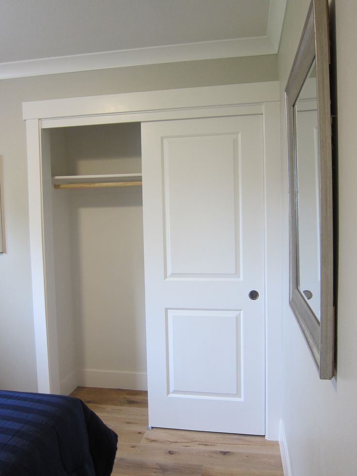 an empty bedroom with a bed, closet and mirror on the wall next to it