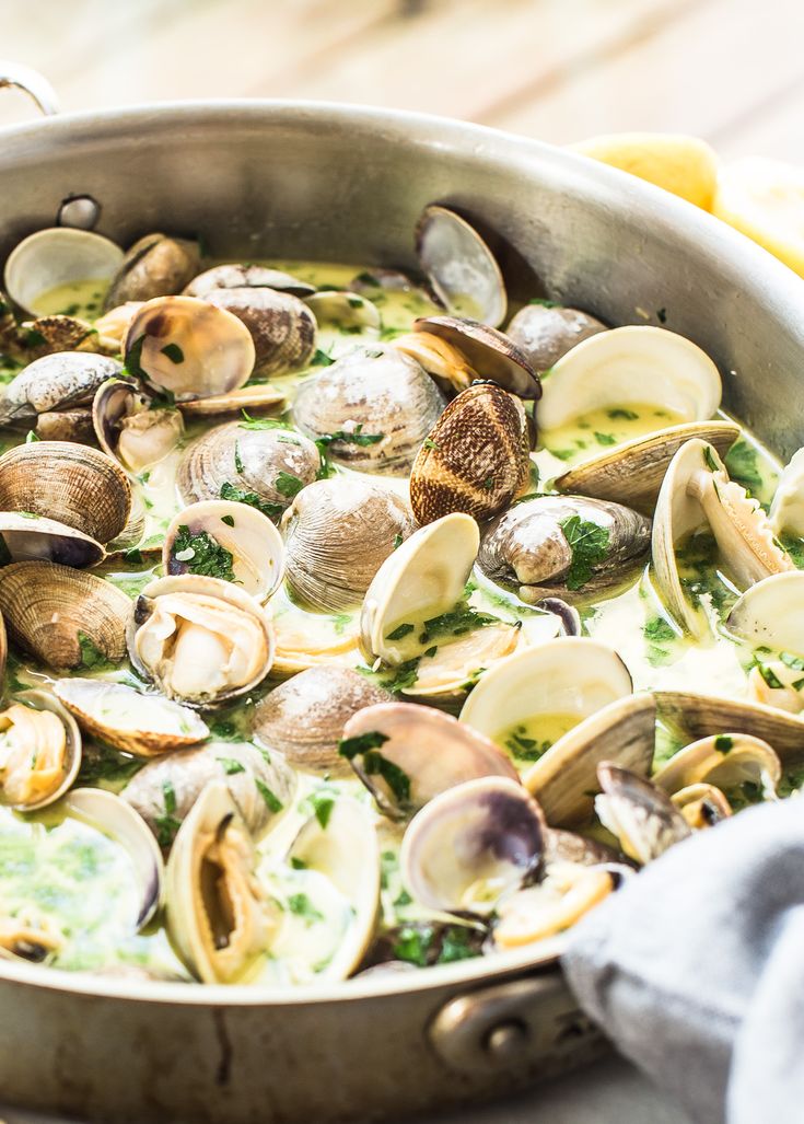 clams are being cooked in a pan on the table