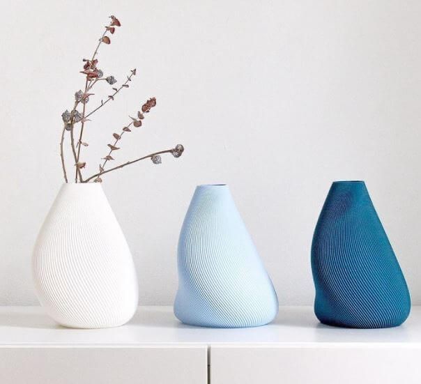 three vases sitting on top of a white shelf next to each other with flowers in them