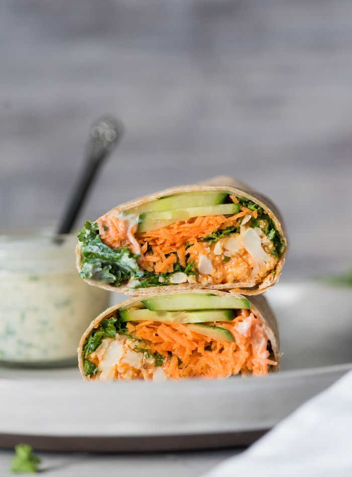 two wraps with carrots, lettuce and cucumber are on a plate