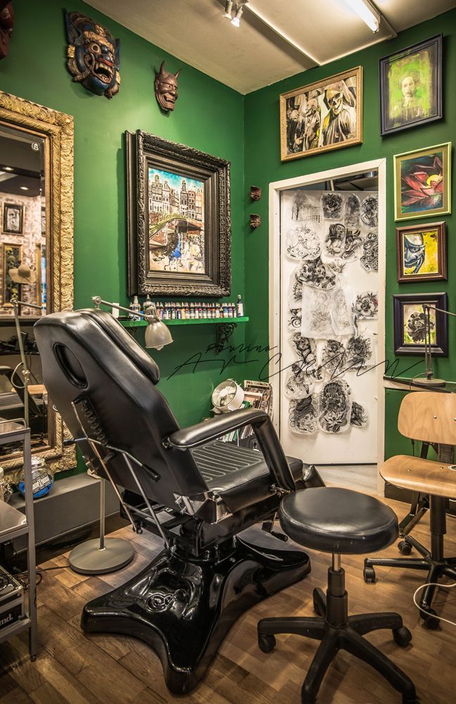 a barber chair sitting in front of a green wall with pictures on the walls behind it