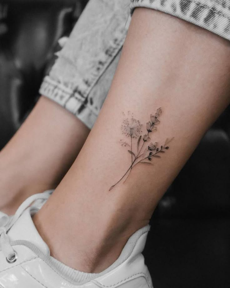 a woman's foot with a small flower tattoo on the left side of her ankle