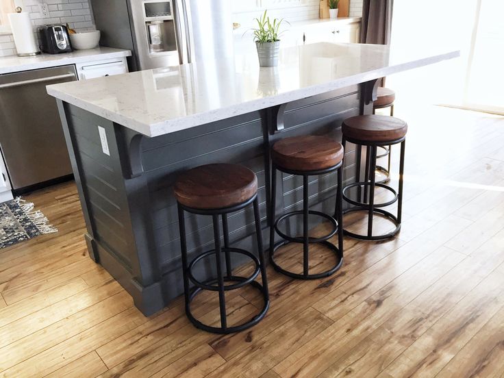 a kitchen island with three stools in front of it