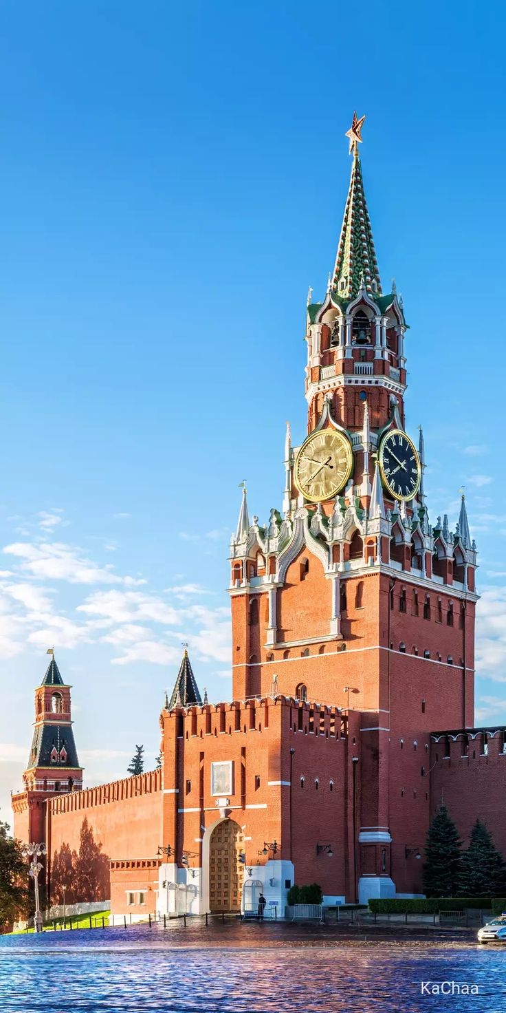 a large building with a clock on it's side next to the water and blue sky