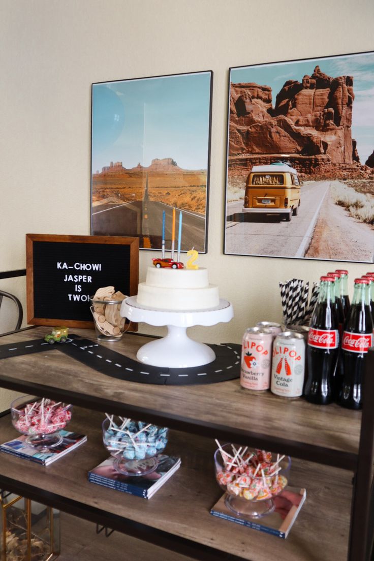 a table topped with cakes and drinks on top of a wooden table next to pictures