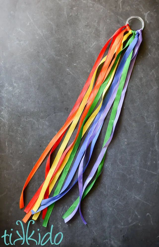 colorful streamers are attached to a metal hook on a gray surface with the words tikido written below it