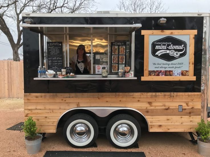 a food truck parked in front of a fenced off area with potted plants