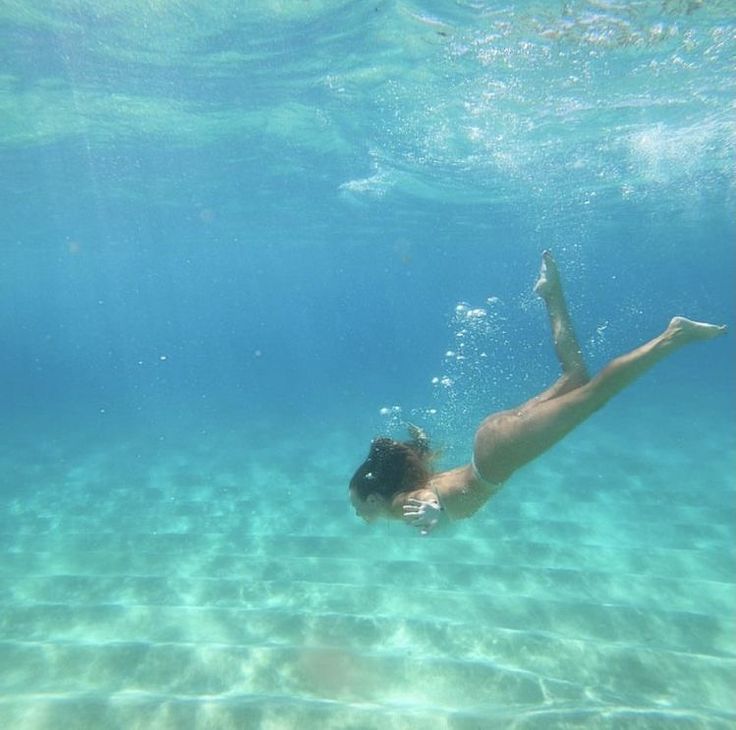 a woman swimming under water in the ocean