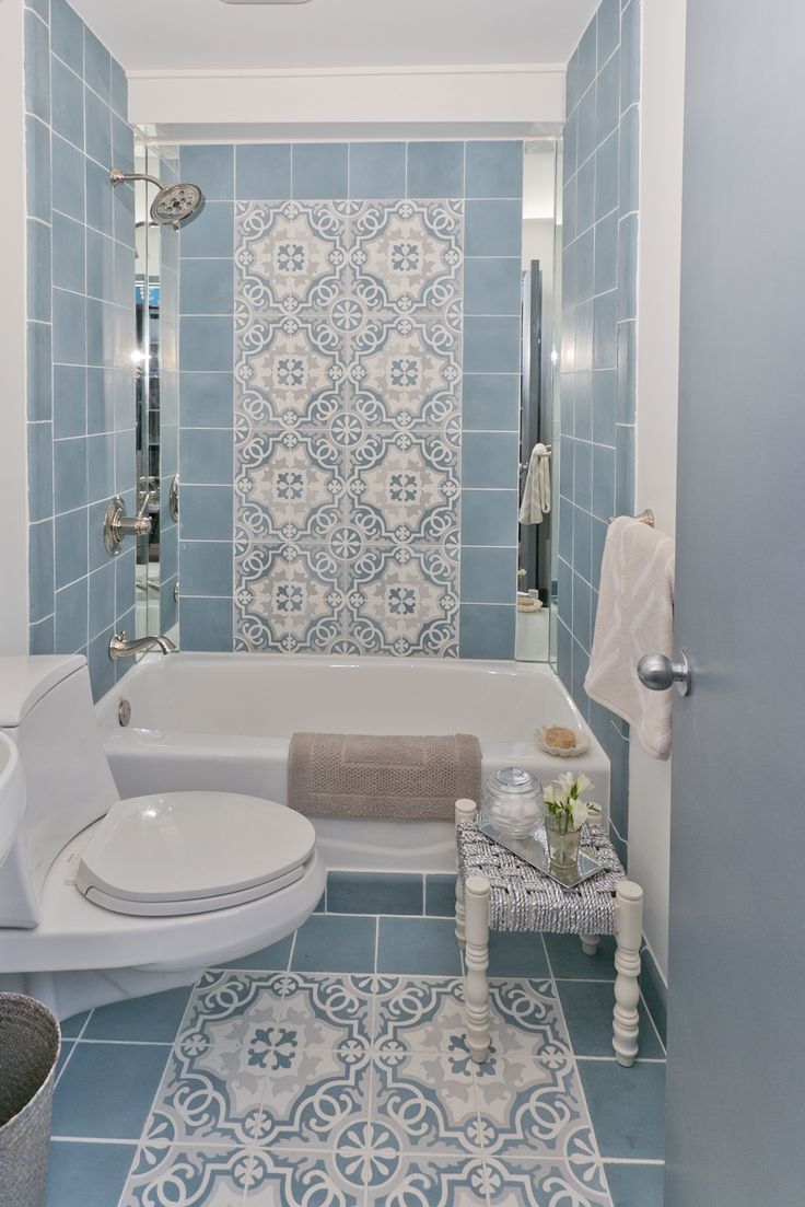 a bathroom with blue and white tiles on the walls, flooring and bathtub