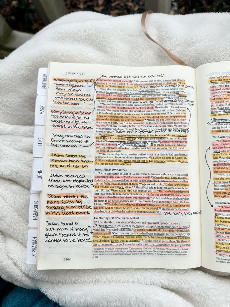 an open book with writing on it sitting on top of a white blanket next to a potted plant