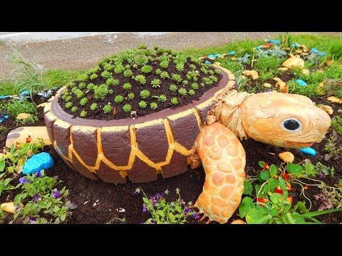 a turtle planter sitting in the middle of a garden filled with flowers and plants