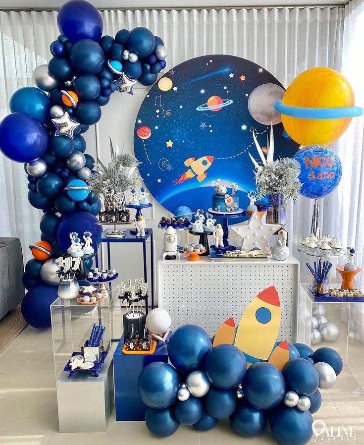 a space themed birthday party with blue balloons, silver and white decorations and an astronaut balloon arch