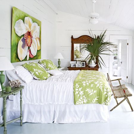 a bedroom with white walls and green bedding in front of a painting on the wall