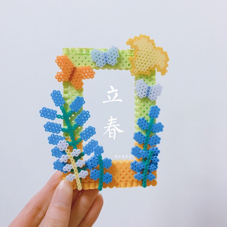 a person holding up a small frame made out of plastic beads