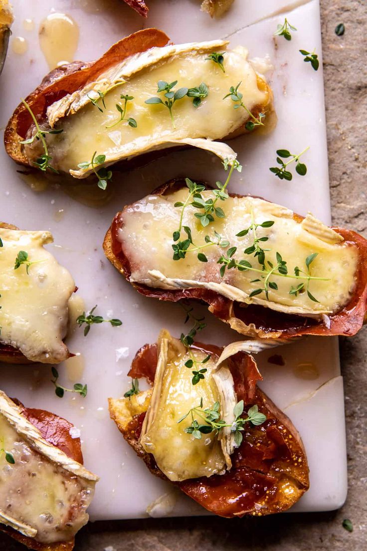 several pieces of bread with cheese and bacon on it sitting on a white platter