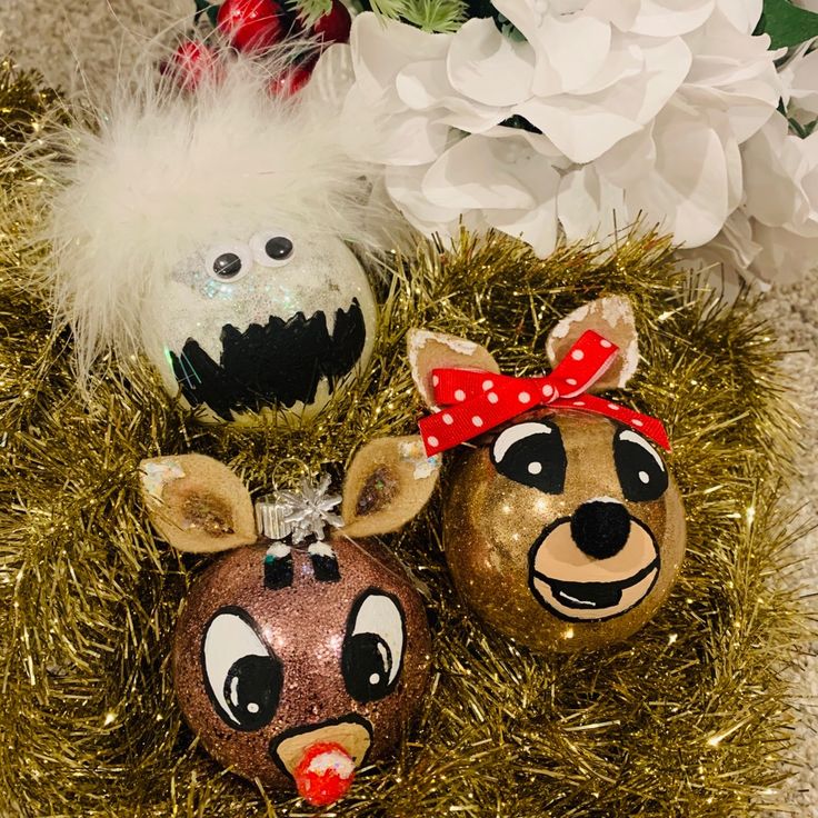 three christmas ornaments are sitting on some tinsel