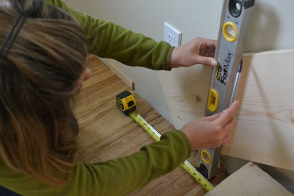 a woman is measuring the height of a piece of wood with a tape measure ruler