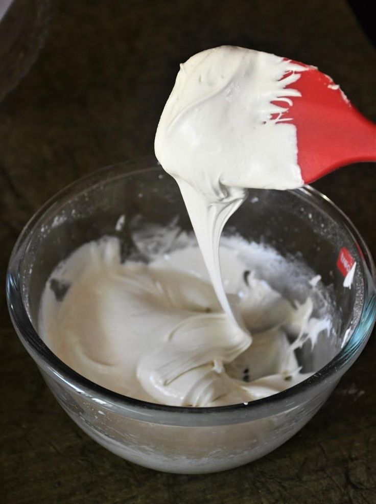 a red and white spatula in a glass bowl filled with whipped cream