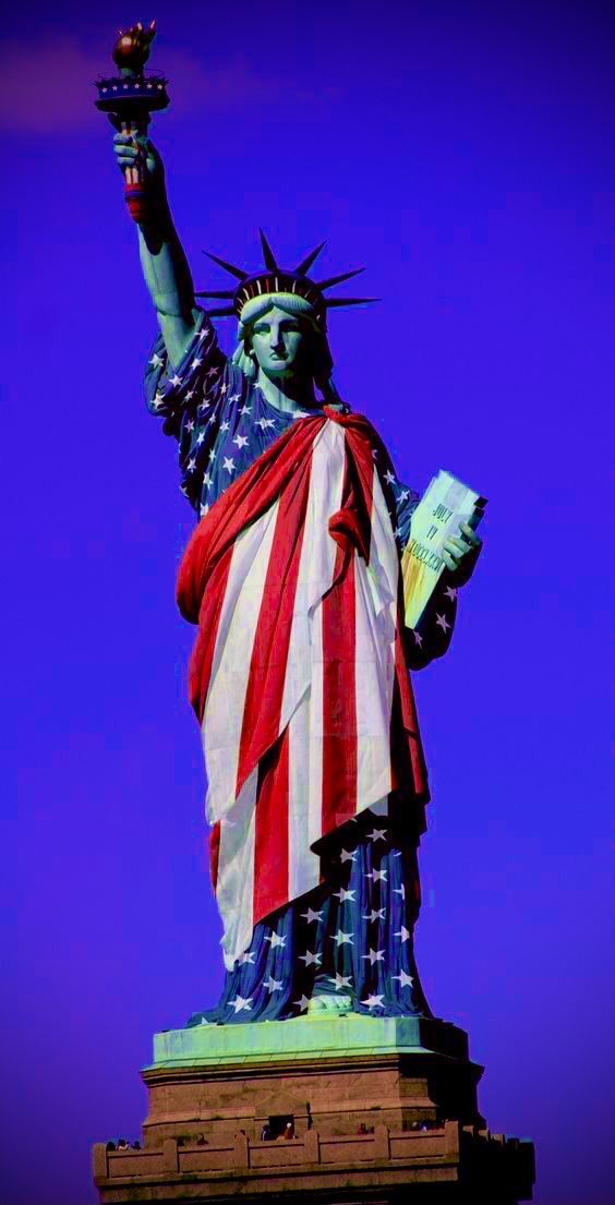 the statue of liberty is holding a book in its hand and wearing an american flag cape