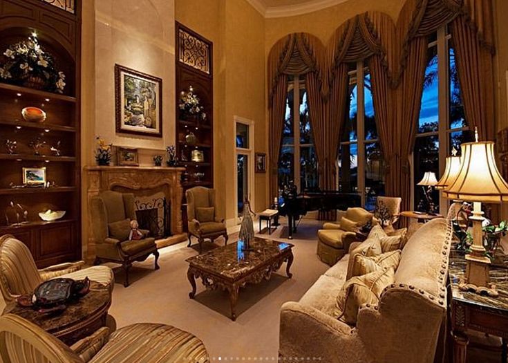 a living room filled with lots of furniture next to tall windows and a fire place