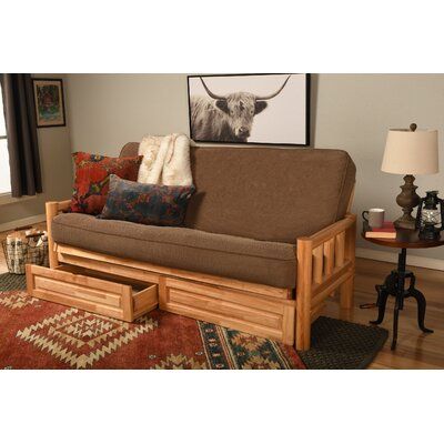 a living room with a futon and pillows on top of the couch, in front of a window