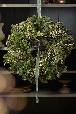 a christmas wreath on top of a book shelf