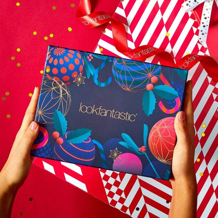 a person holding up a box with the word look fantastic on it, surrounded by red and white striped wrapping