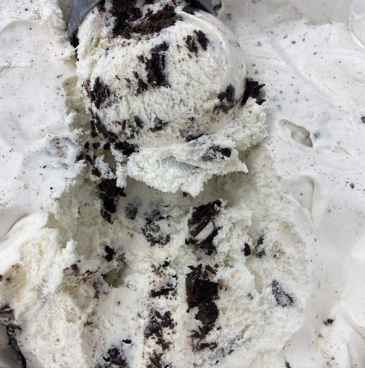 an ice cream scoop full of chocolate chip cookies and white icing in a bowl