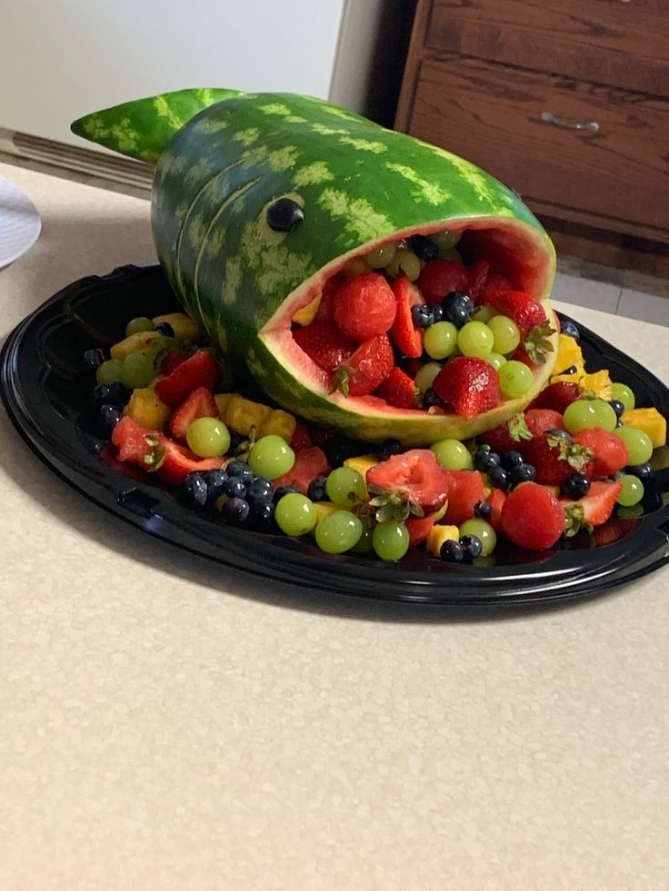 a watermelon shaped like a shark with fruit in it's mouth on a plate