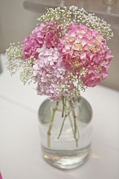 a vase filled with pink hydrangeas and baby's breath in glass vase