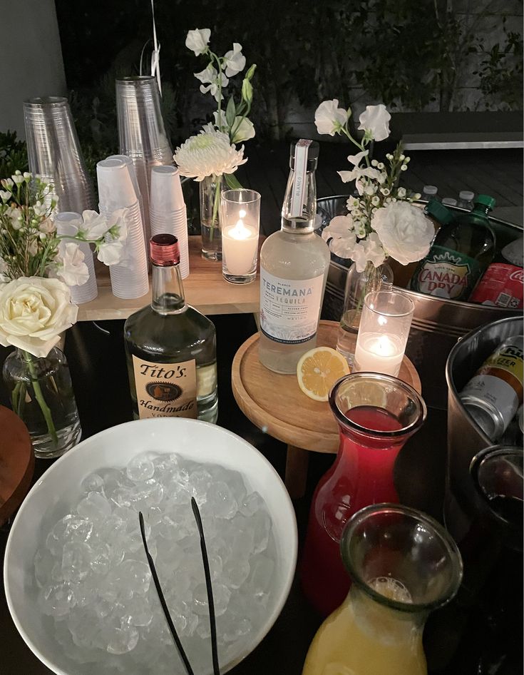 a table topped with bottles and glasses filled with liquid next to candles on top of a wooden table