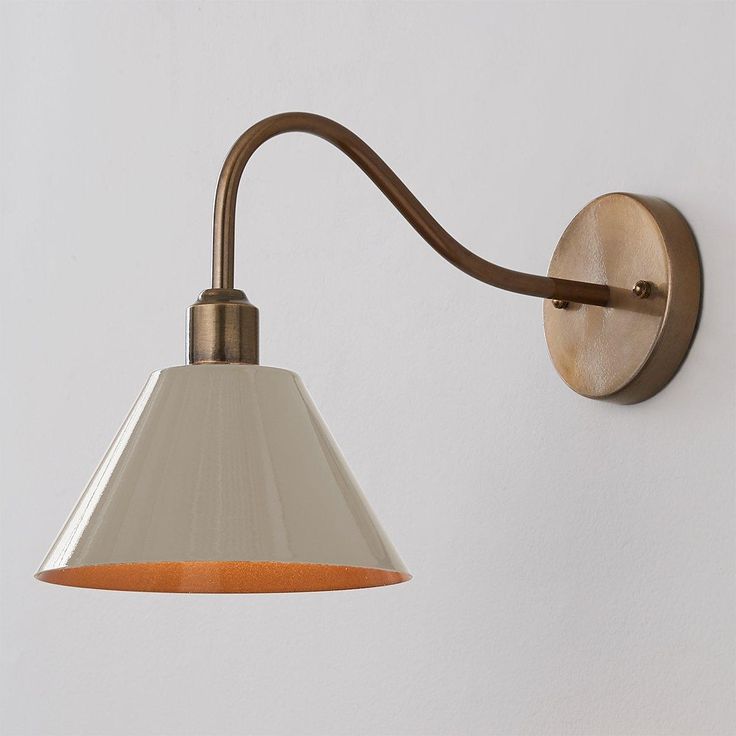 a wall light with an orange shade on it's side and a white background