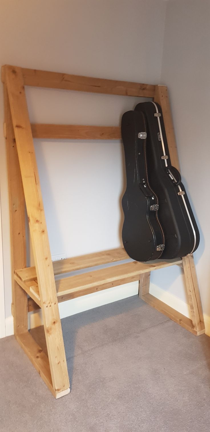 a guitar case sitting on top of a wooden shelf next to a ladder in a room