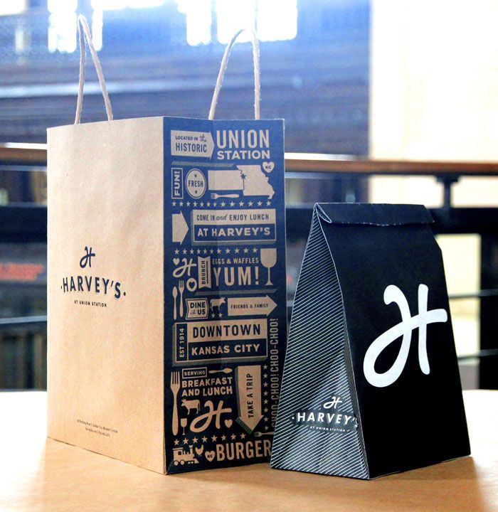 two paper bags sitting on top of a table next to each other, one black and the other white