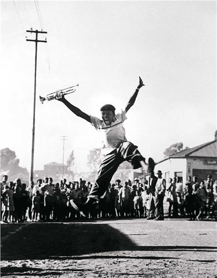 a man jumping in the air with a tennis racquet on his hand while people watch