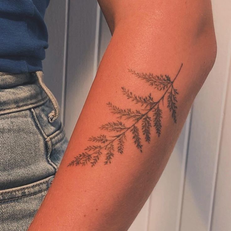 a woman's arm with a tattoo on it that has green leaves growing out of it