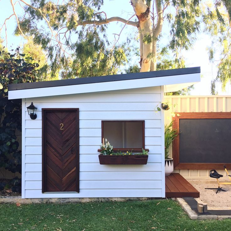 a small white shed with two windows on the side and a door to another room