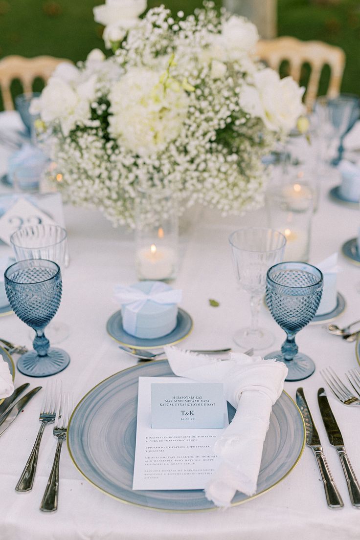 the table is set with blue and white plates, silverware, and flowers in vases