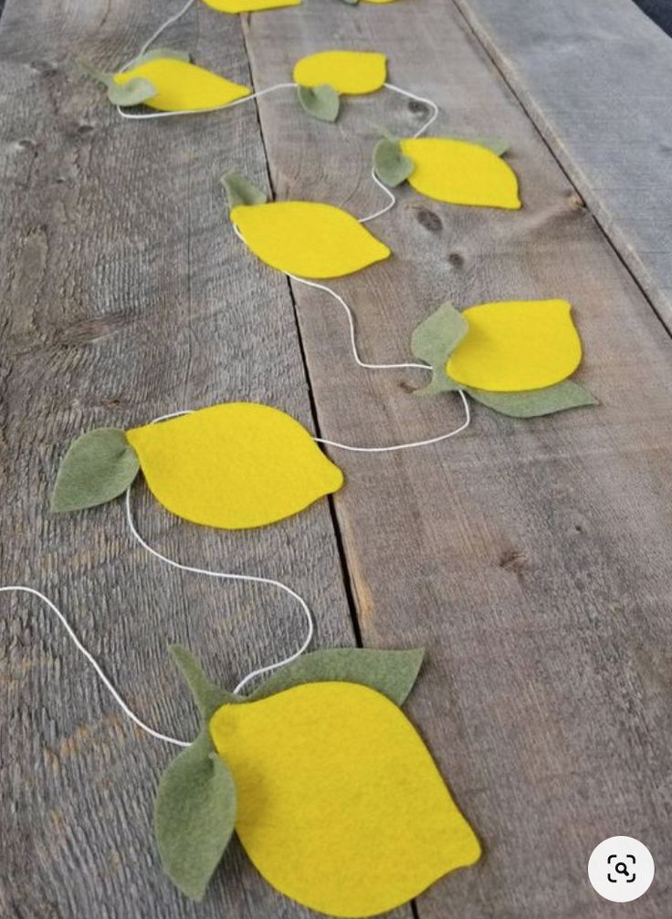 some yellow flowers are sitting on a wooden table with string attached to the stems and leaves