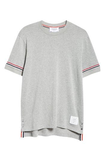 Thom Browne's varsity-stripe motif brings the label's signature refinement to a classic cotton T-shirt updated with a subtle high-low hem shut with buttons. 29" length (size 2) Crewneck Short sleeves High-low hem with button side vents 100% cotton with 97% cotton, 3% elastane trim Dry clean or machine wash, tumble dry Made in Italy Designer Clothing Classic Short Sleeve Tops With Striped Cuffs, Classic Cotton T-shirt With Striped Collar, Relaxed Fit Crew Neck Top With Striped Cuffs, Classic Streetwear Tops With Three Stripes Branding, Classic Three Stripes Tops For Streetwear, Classic Tops With Three Stripes Branding For Streetwear, Classic Crew Neck Top With Three Stripes, Sporty Relaxed Fit Top With Striped Hem, Sporty Tops With Striped Hem And Relaxed Fit