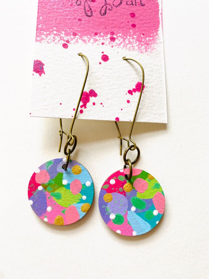 the earrings are decorated with colorful paint splattered on them