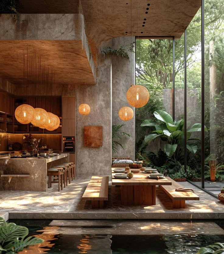 an outdoor kitchen and dining area in a house with large glass windows, surrounded by greenery