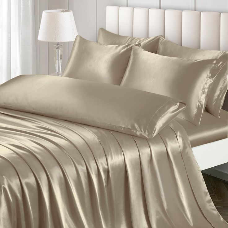 a bed with beige sheets and pillows on top of it in a bedroom next to a white headboard