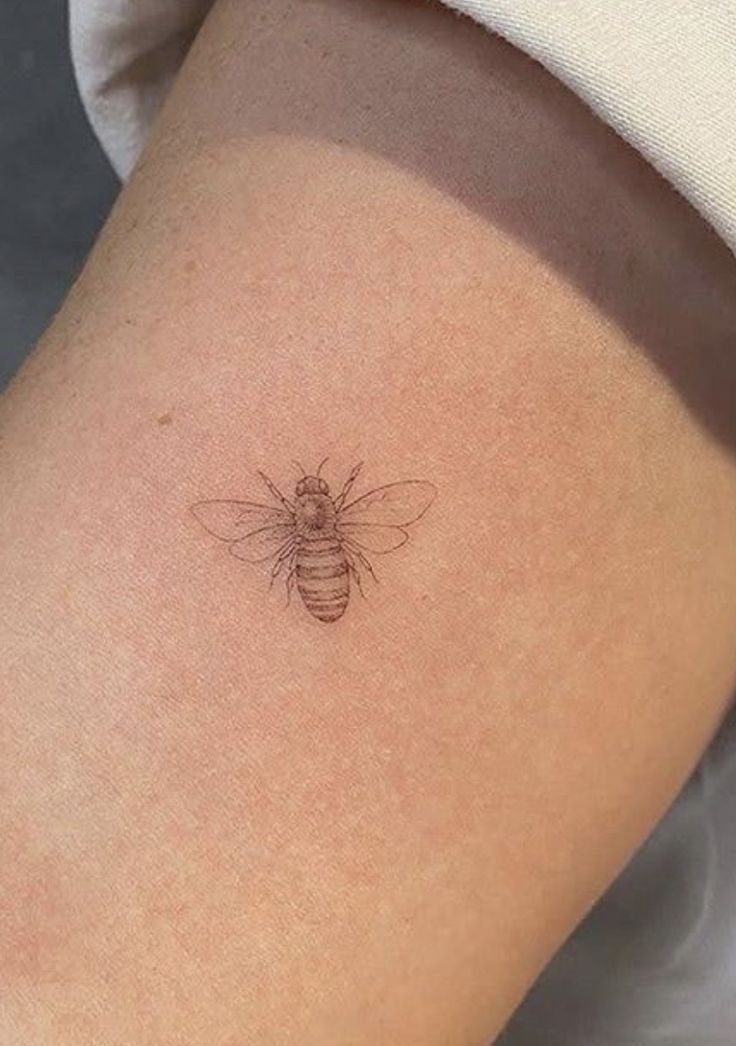 a small bee tattoo on the thigh